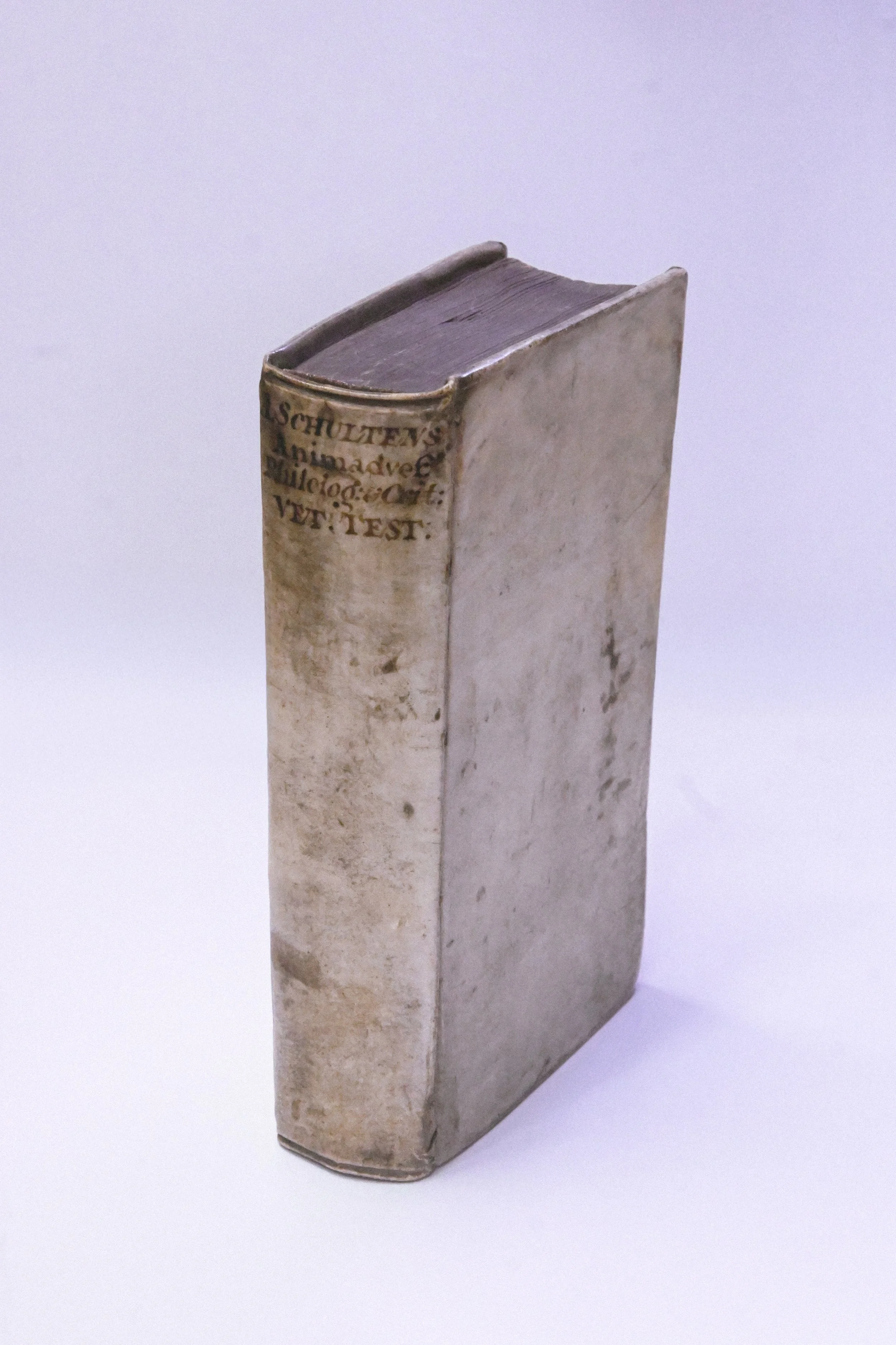 A worn, antique leather-bound book with a partially visible hand-written title on the spine.