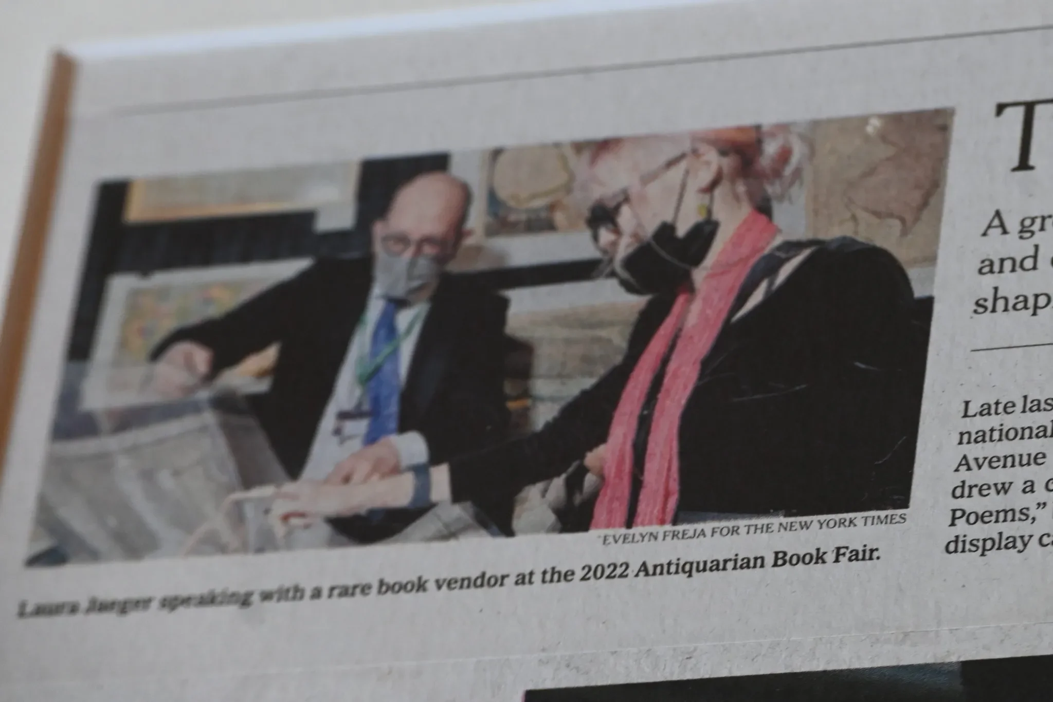 Two people, wearing masks, are looking at a book together at the 2022 Antiquarian Book Fair.
