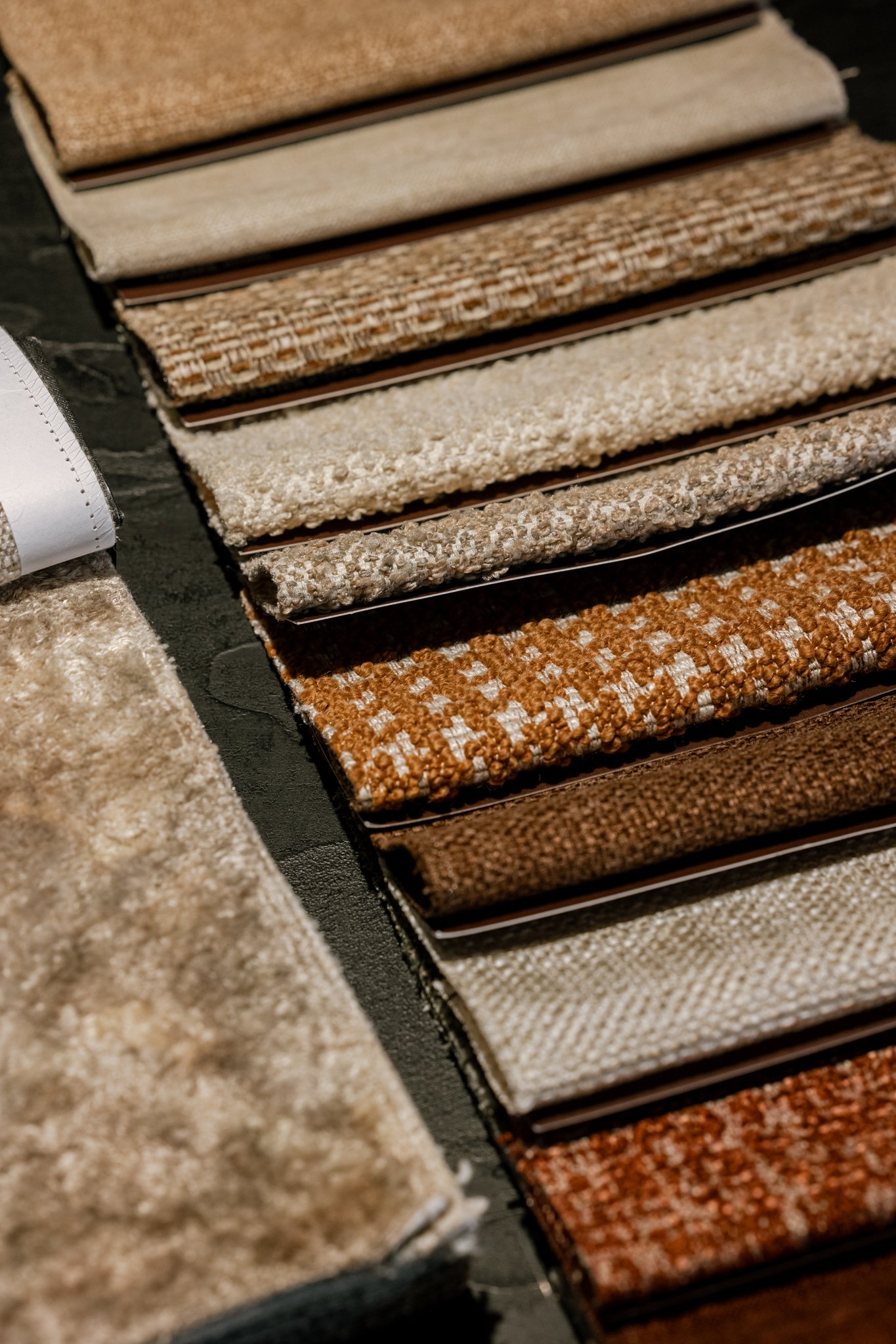 Fabrics in various shades of beige, brown, and cream, displayed in a retail setting.