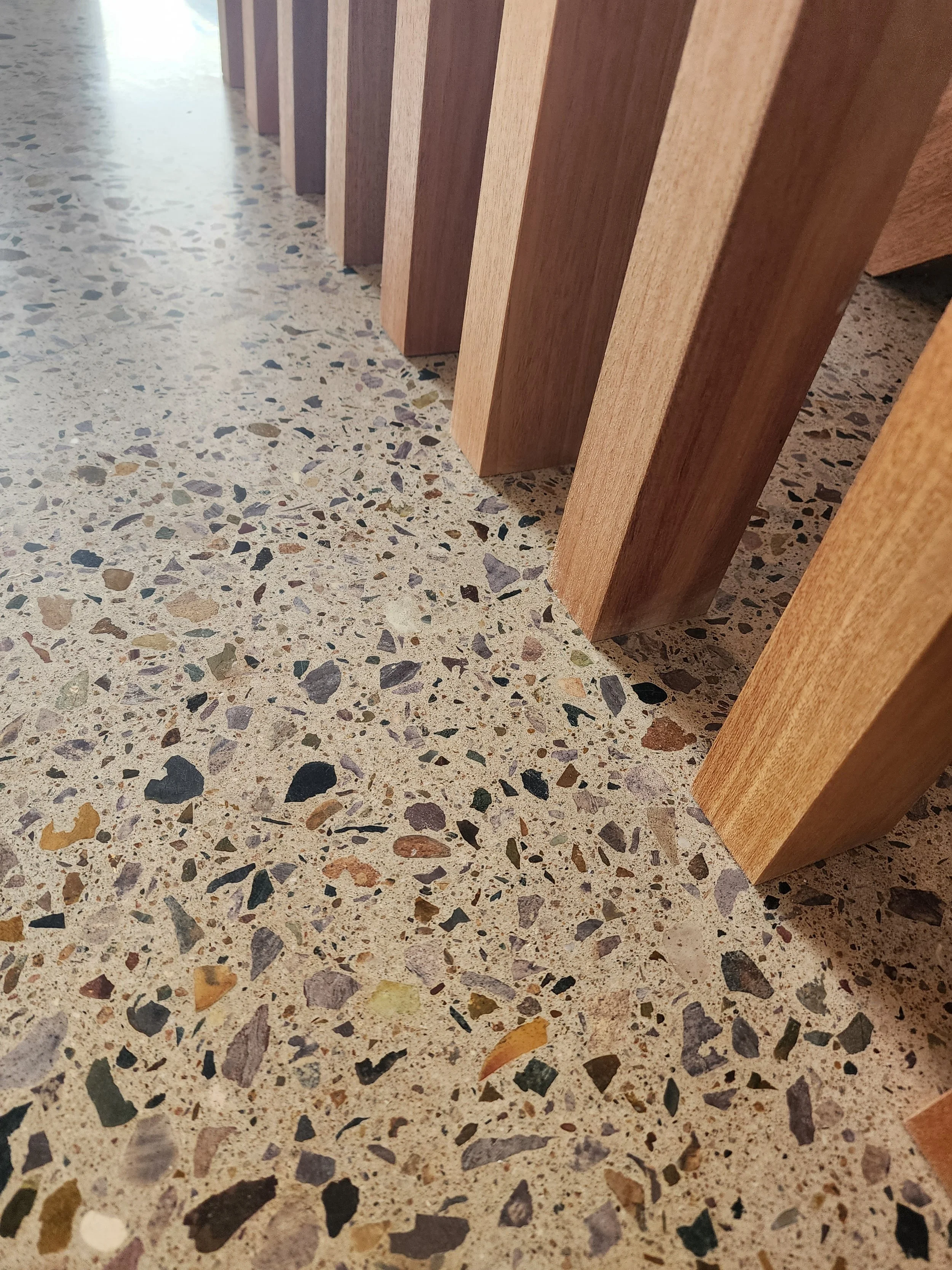 Close-up of a floor polishing machine on a tiled floor, with a worker partially visible in the background.
