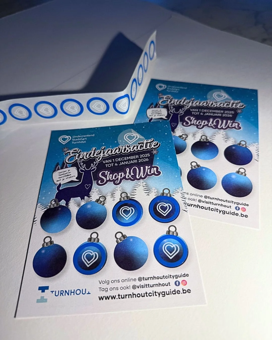 Two Christmas-themed flyers with blue ornaments and a reindeer, advertising a giveaway from December 1, 2025, to January 4, 2026, for Turnhout city guide.