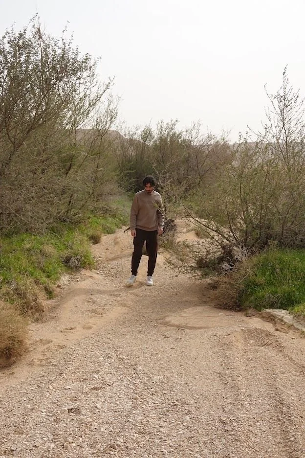 A person walking along a sandy country path through open scrubland