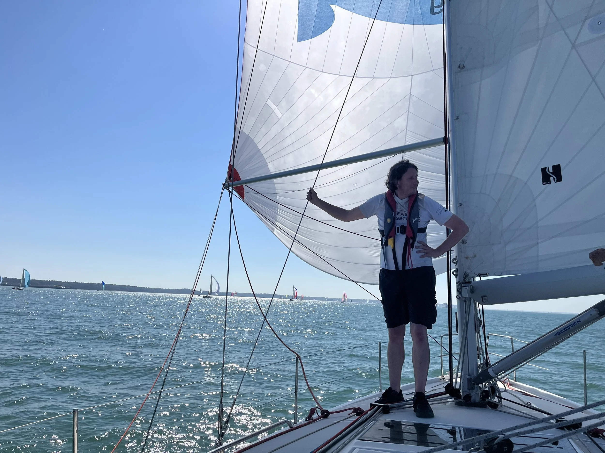 Sailor managing a line on deck in sunshine