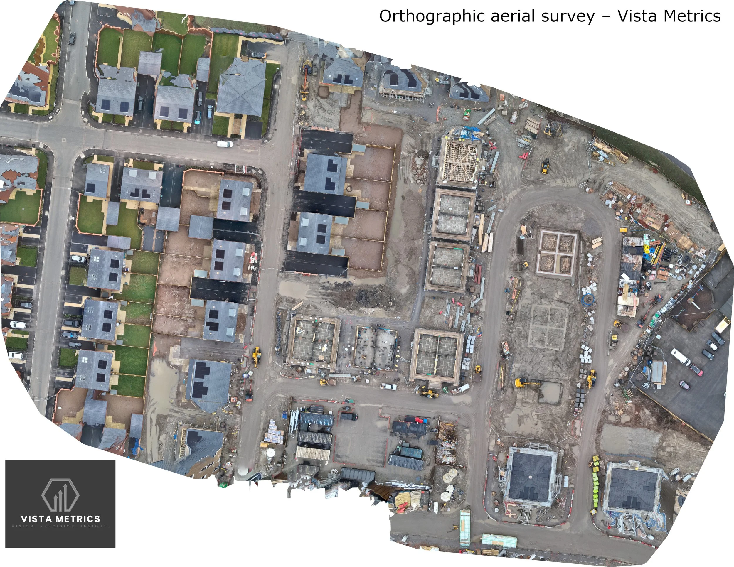Aerial construction site with residential houses, multiple foundation frames, ongoing building work, and construction equipment.