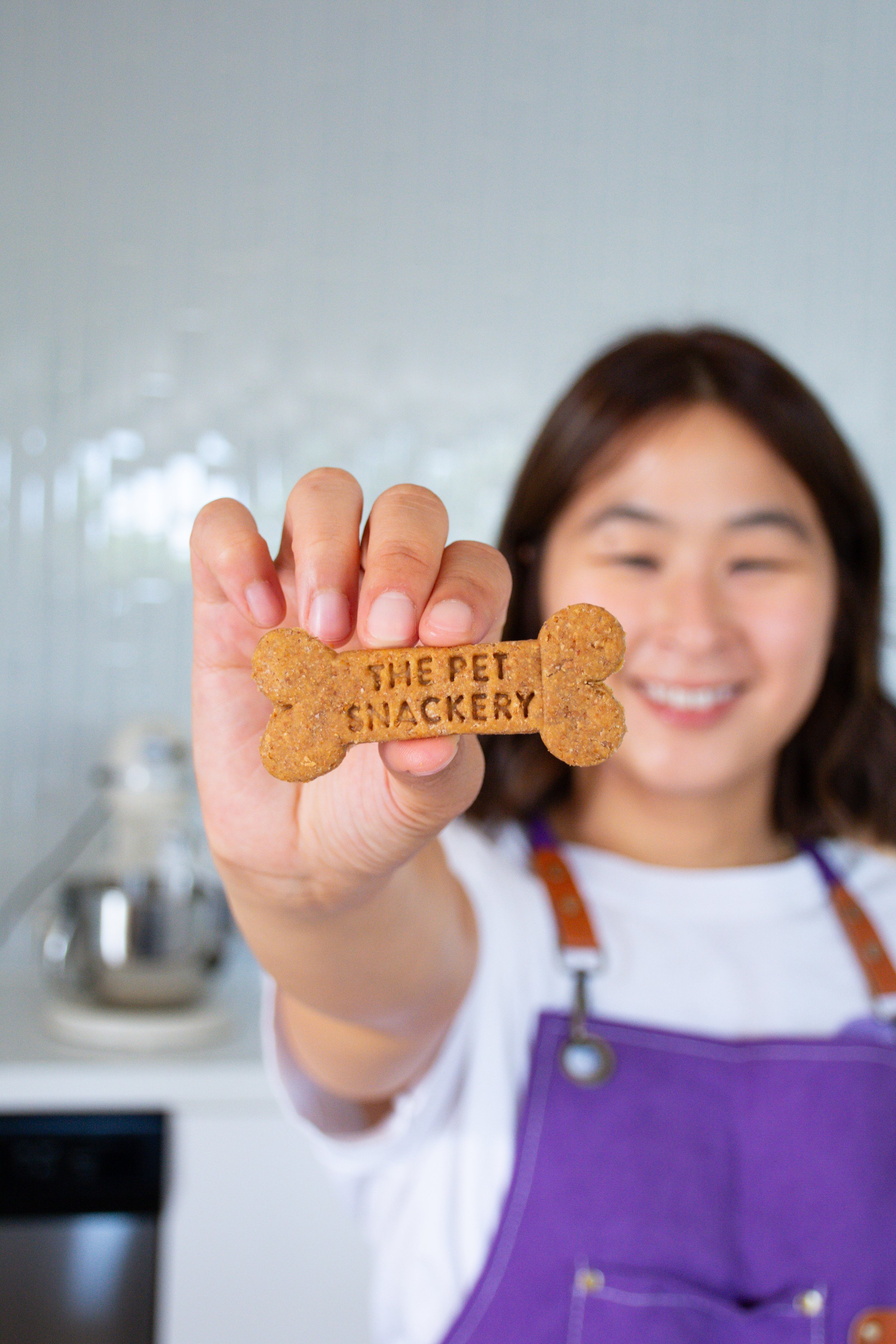 Creative maker holding a handmade dog treat in her workspace
