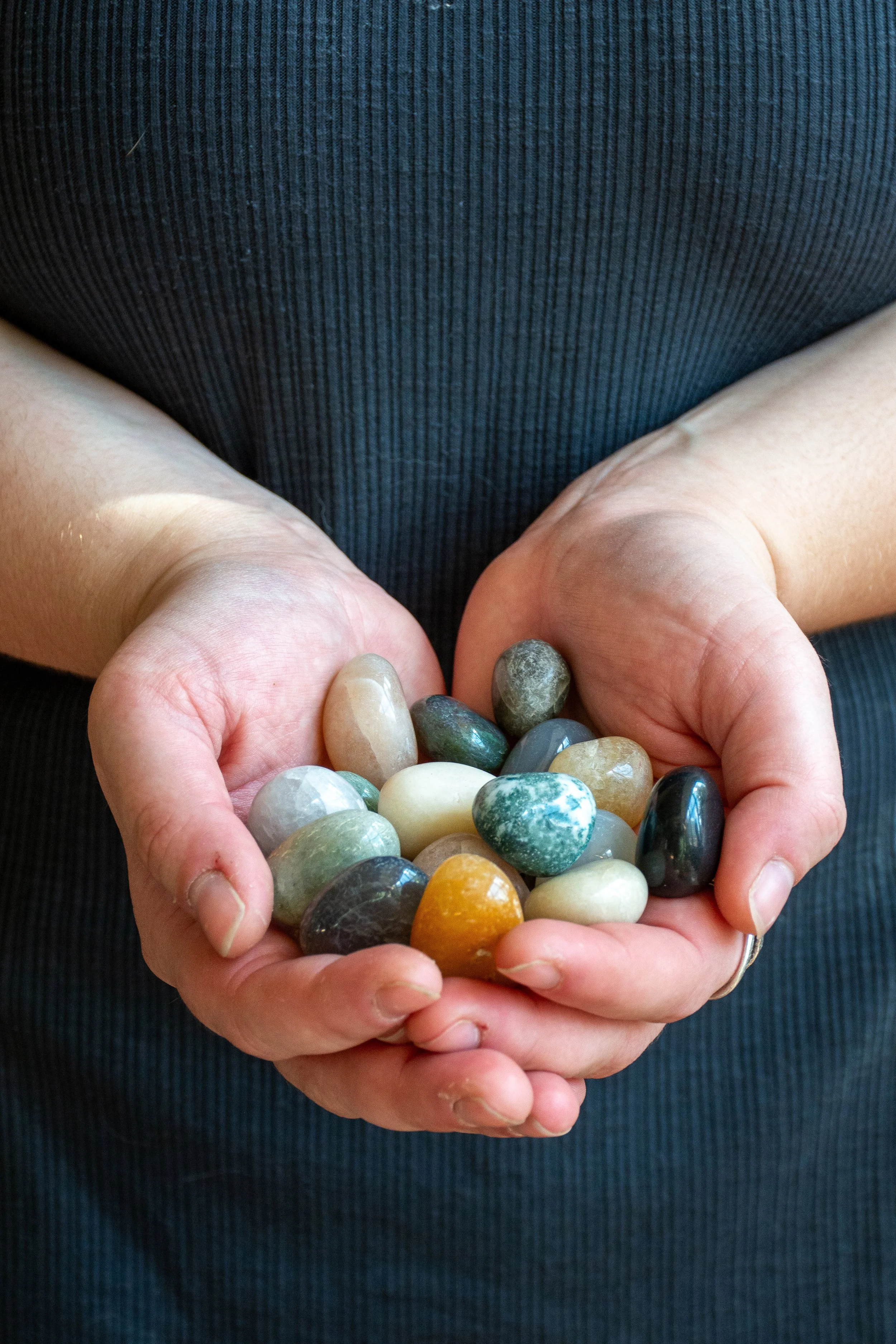 Person holding a handful of polished, multicolored stones.