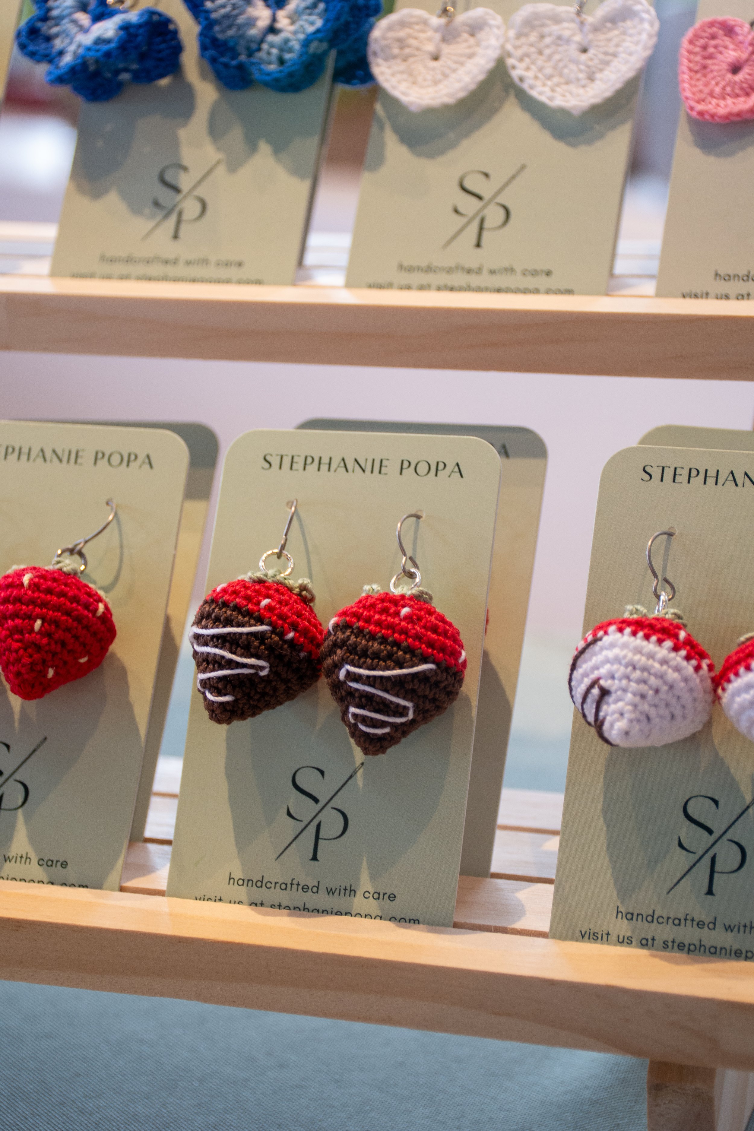 Handmade strawberry and chocolate heart-shaped earrings displayed on cards with the brand name Stephanie Popa.