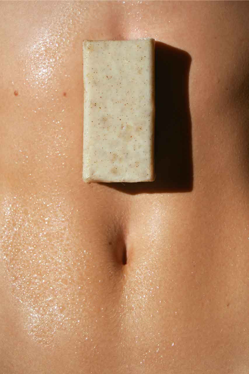 A close-up of a person's belly button with a bar of soap resting on the skin above it.