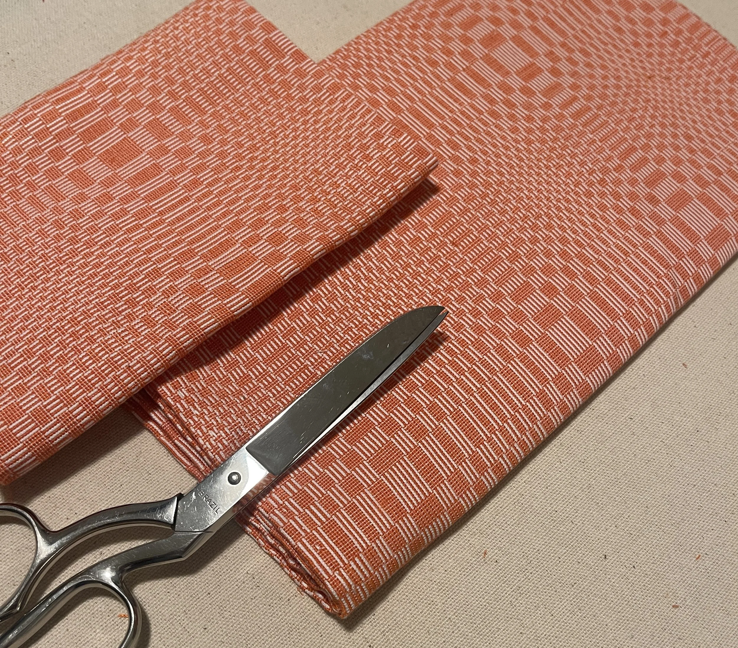 Binakol textile folded and ironed, photographed with a seamstress' scissors.