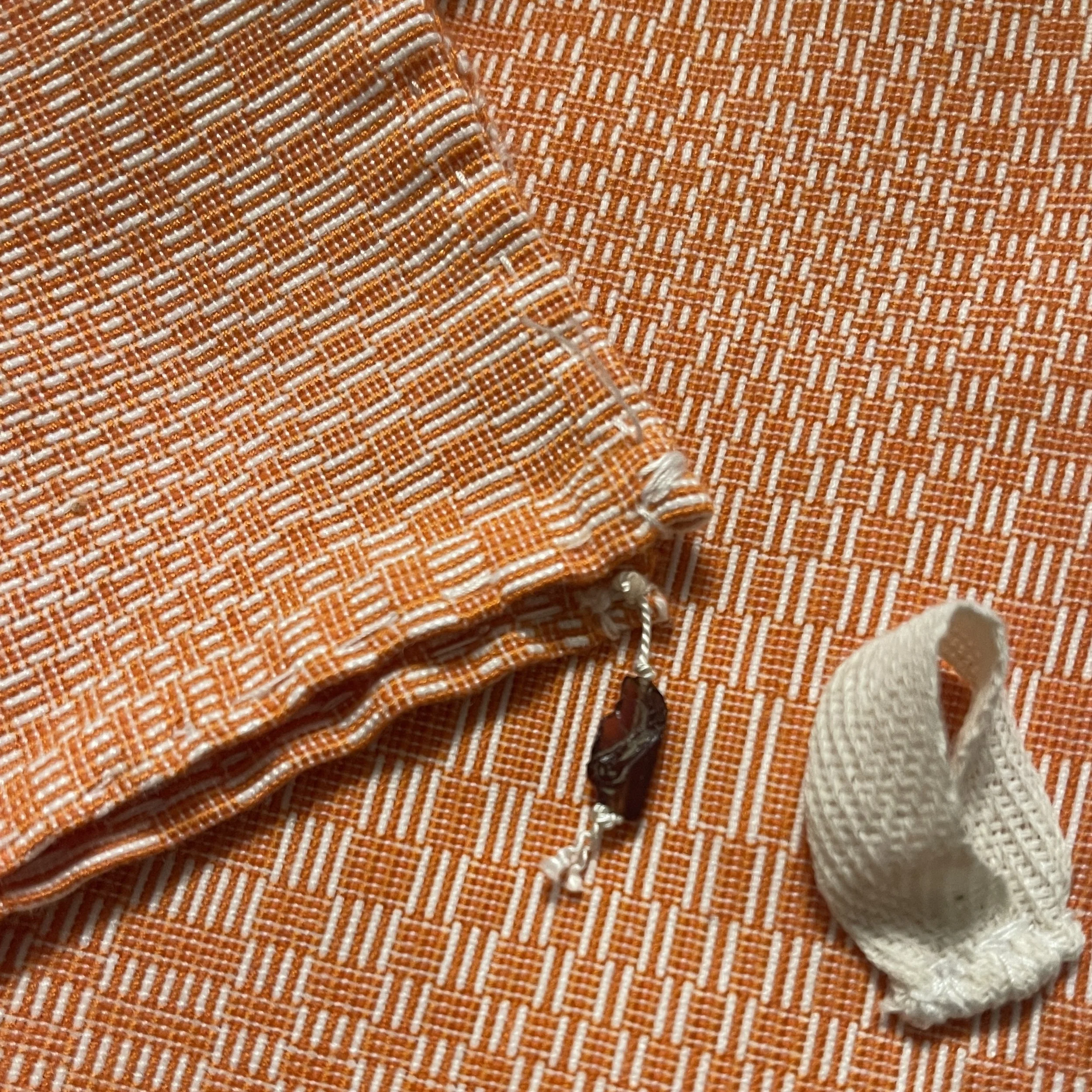 close-up photograph of the binakol geometric weave hawak, a handkerchief finished with a bead on one end and a loop on another to suggest a secondary use as a textile wrap.
