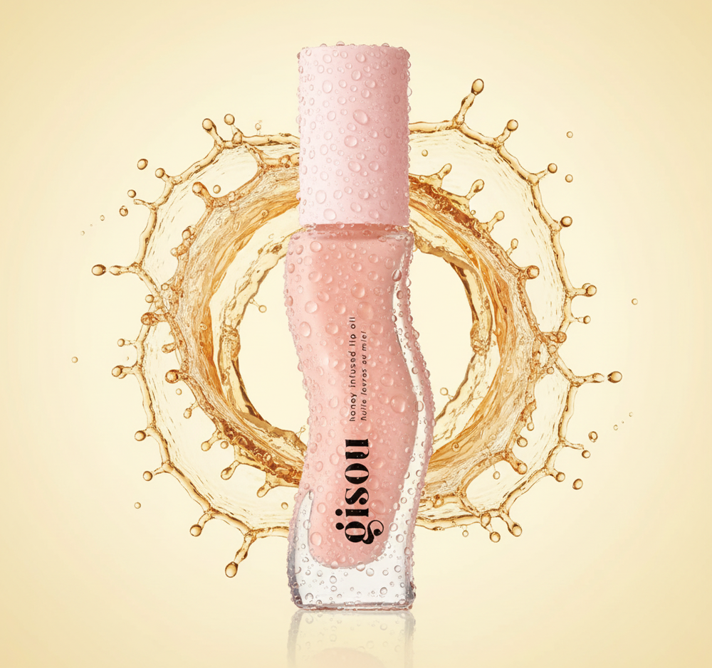 Close-up van een roze Gisou-lipgloss met waterdruppels, omringd door opspattende vloeistof in een cirkelvormige beweging tegen een lichtbeige achtergrond.