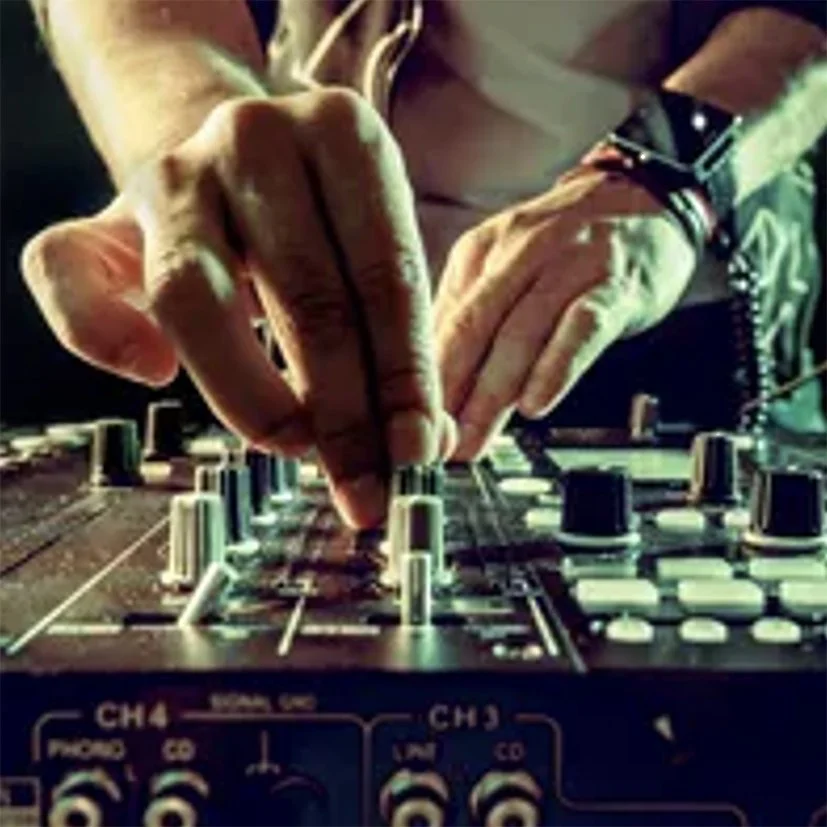 Close-up of a DJ's hands adjusting controls on a sound mixing console.