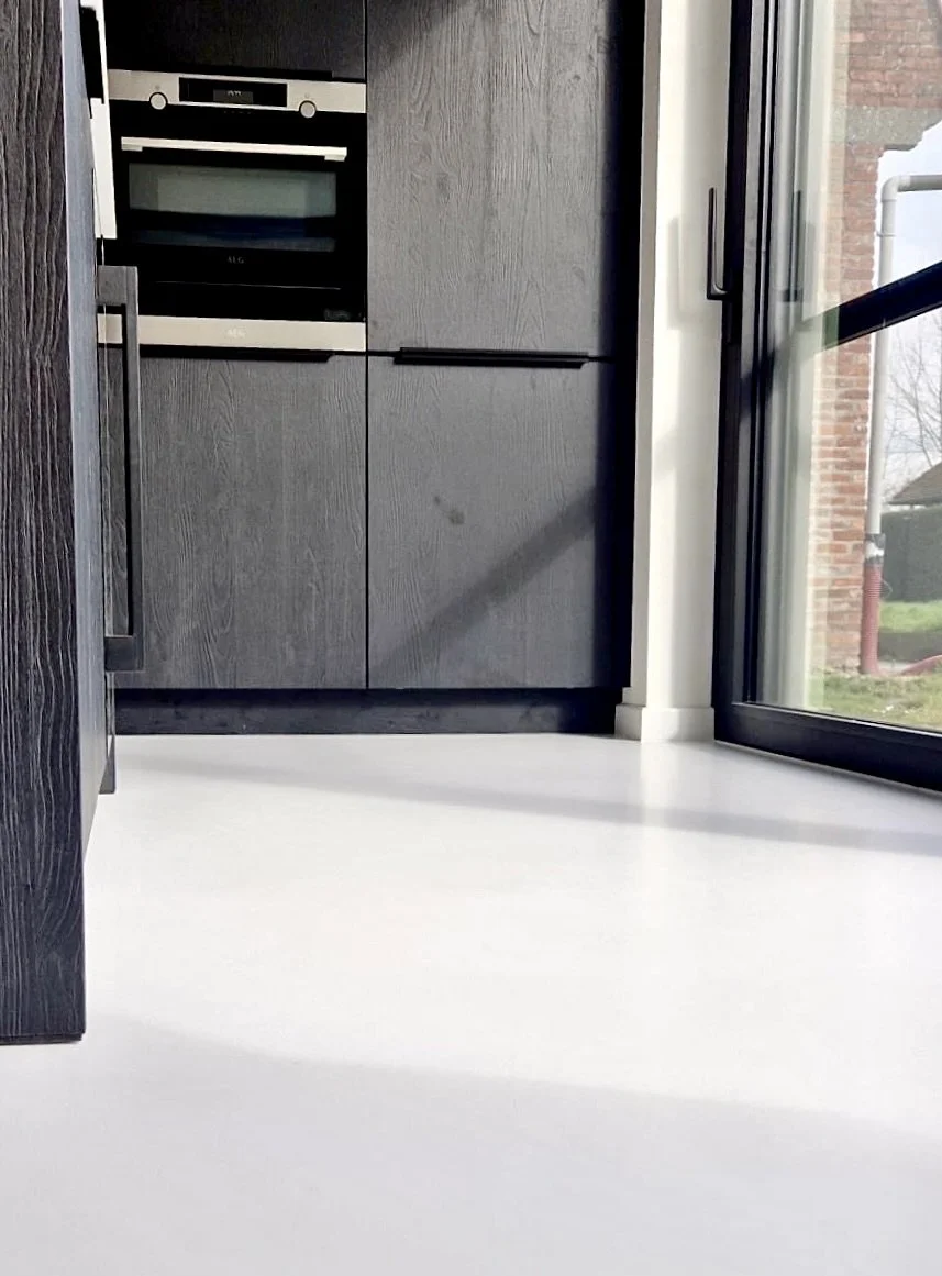 Close-up of a modern kitchen corner with dark gray cabinets, a built-in oven, and a glass sliding door leading outside.