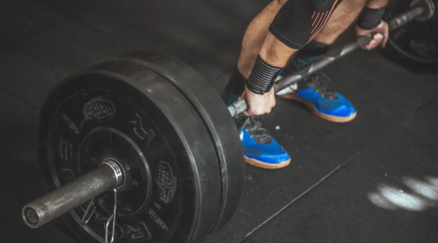 A person performing a deadlift with a loaded barbell in a gym.