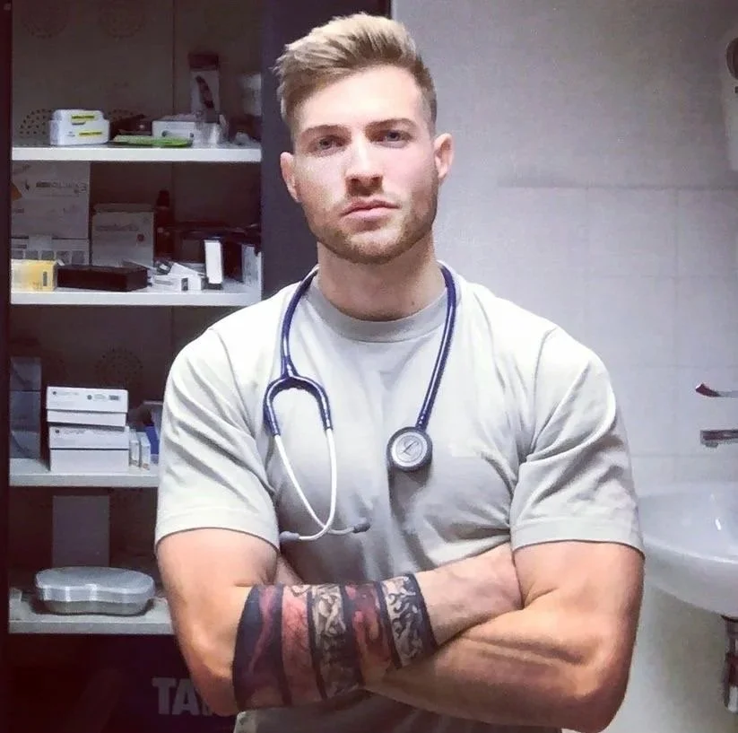 Young male nurse or medical professional in scrubs with a stethoscope around his neck, arms crossed, in a medical supply room. Médecin généraliste Français à Dubaï / GP / French GP / French Doctor / French family medicine