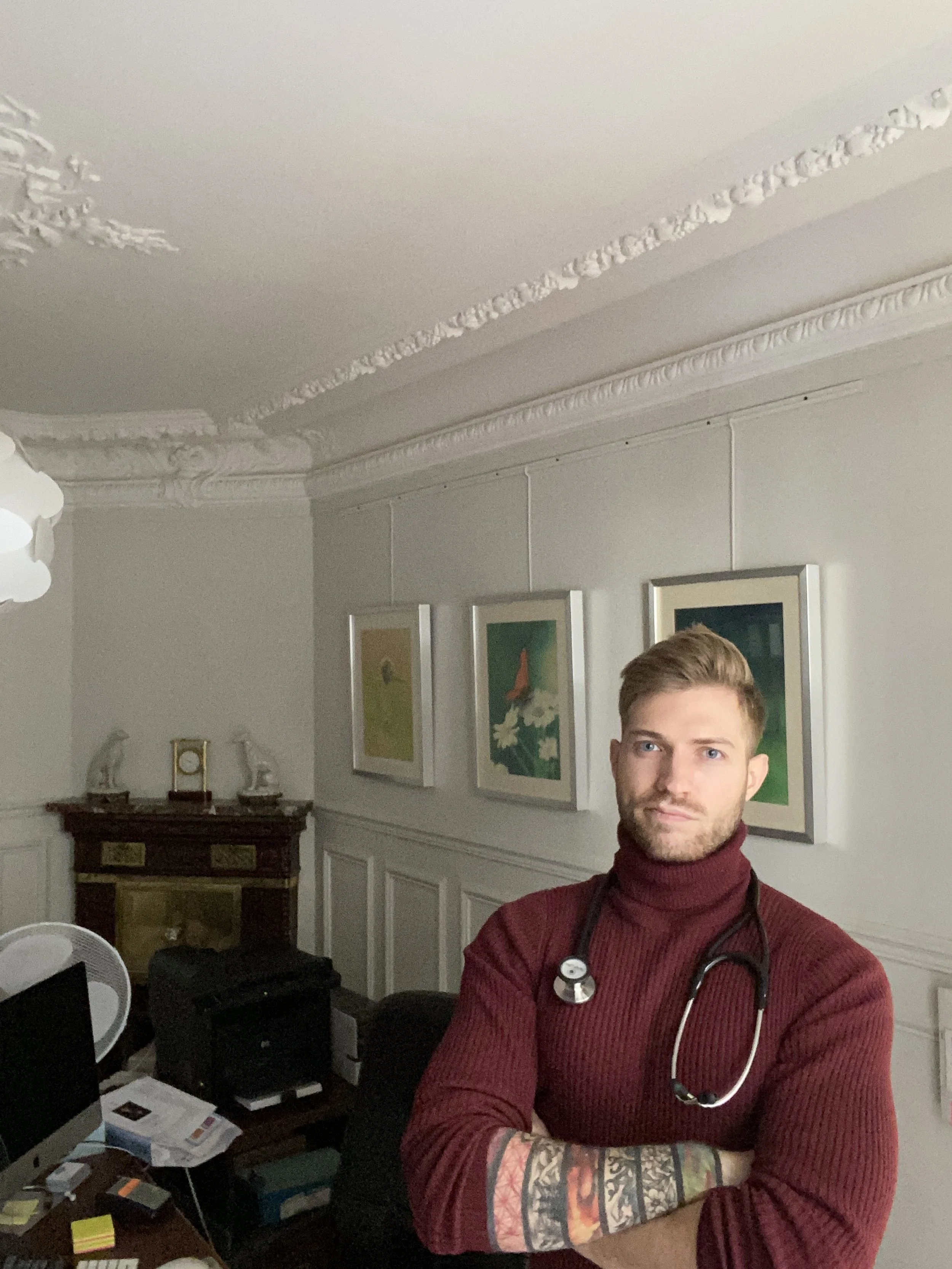 A young man with tattoos on his arm, a stethoscope around his neck, wearing a maroon turtleneck, Médecin généraliste Français à Dubaï / GP / French GP / French Doctor / French family medicine