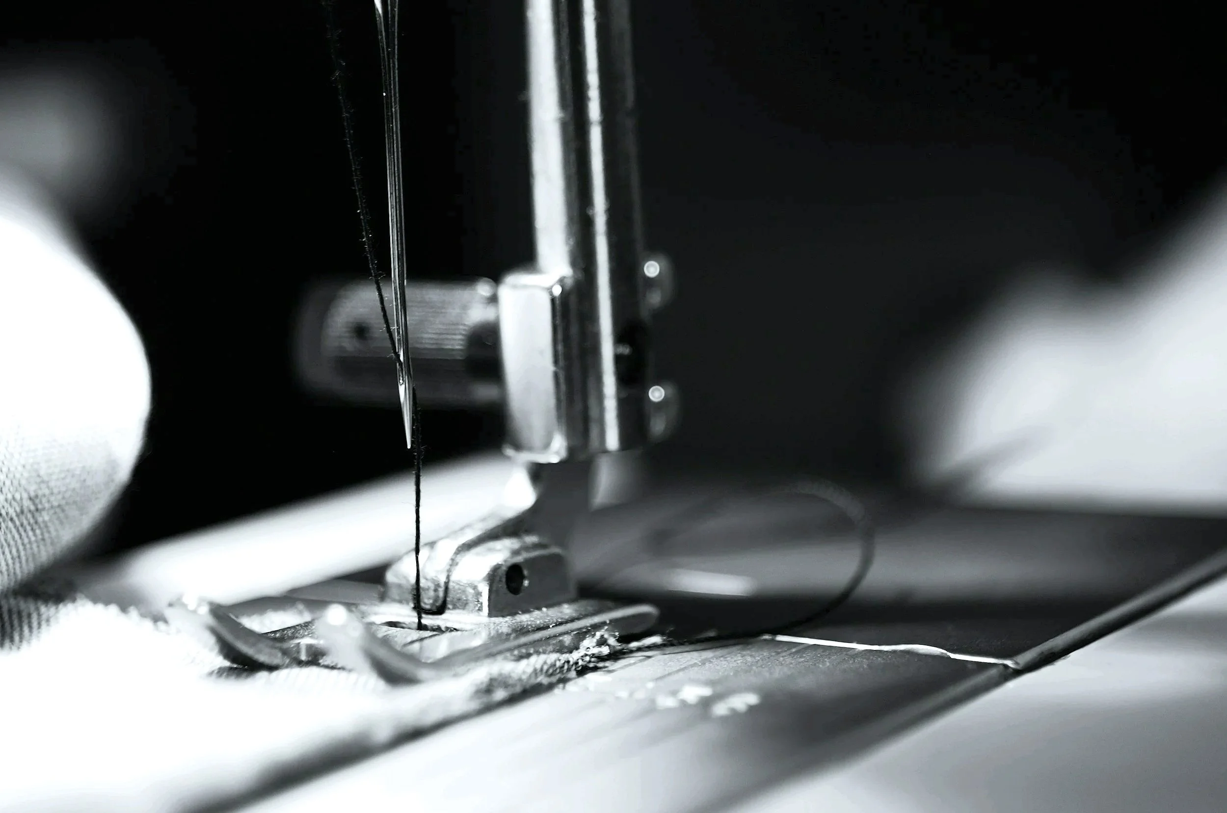 Close-up of a sewing machine needle sewing white fabric.