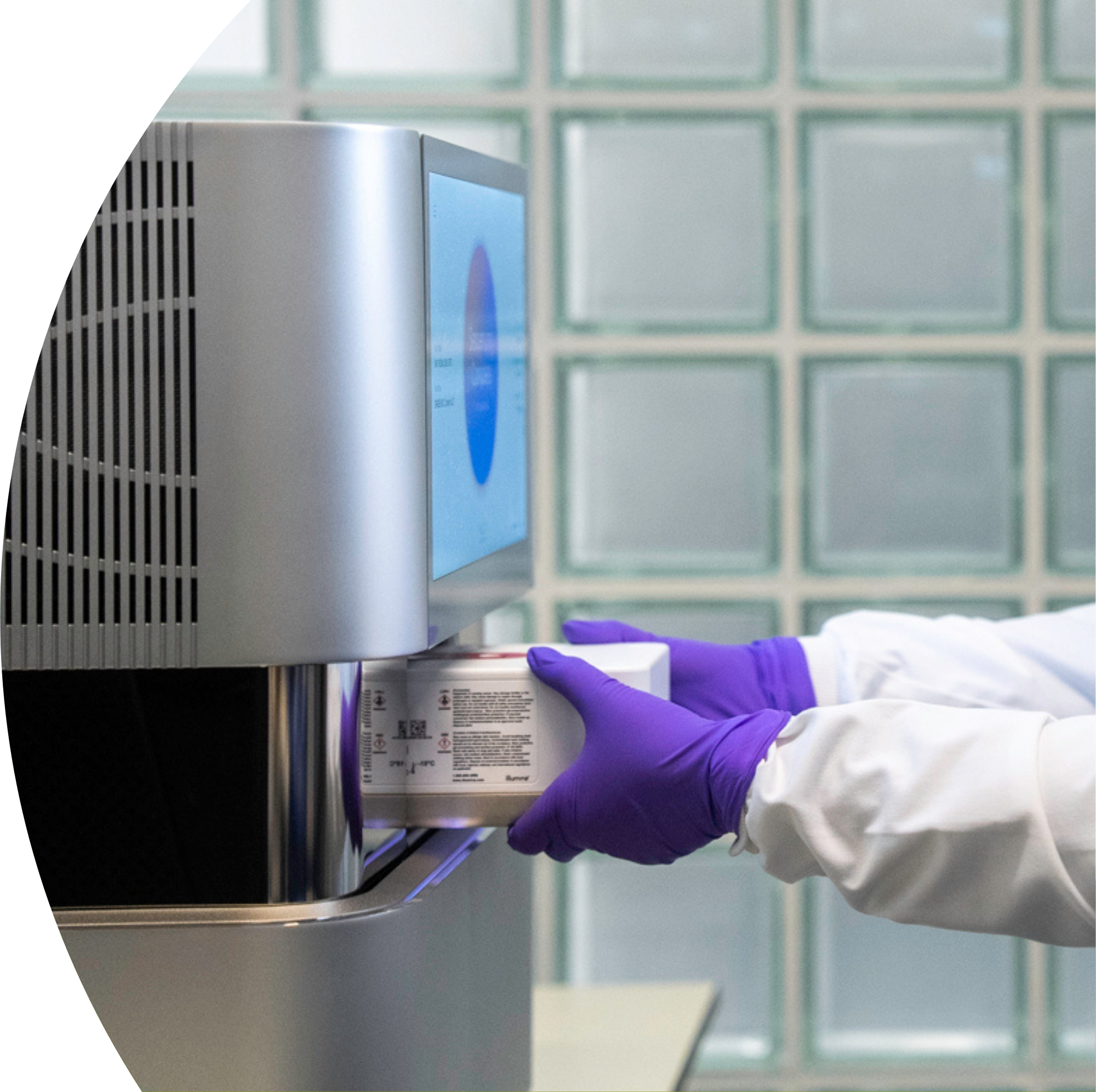 A person wearing purple gloves and a white lab coat operating a NextSeq 2000 machine
