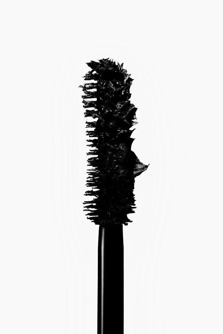 Close-up of a black mascara wand brush with dense bristles against a white background.