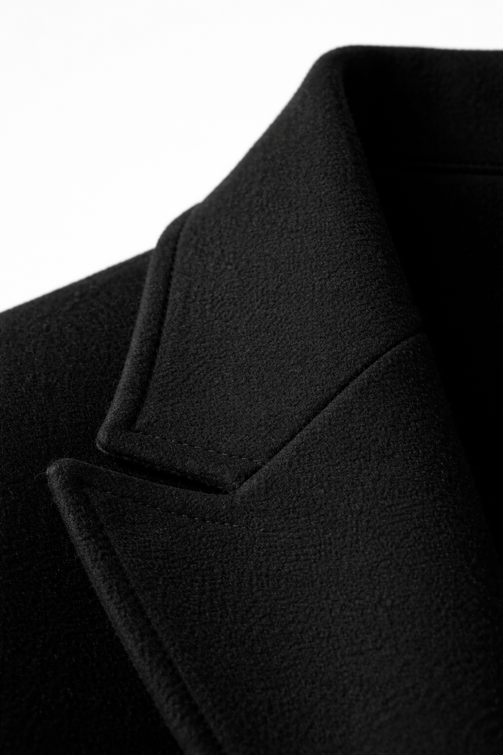 Close-up of a black coat with textured fabric and a lapel