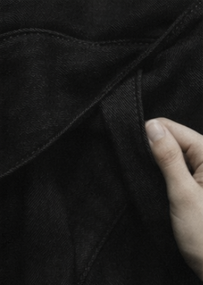 Close-up of a hand holding black denim fabric or clothing.
