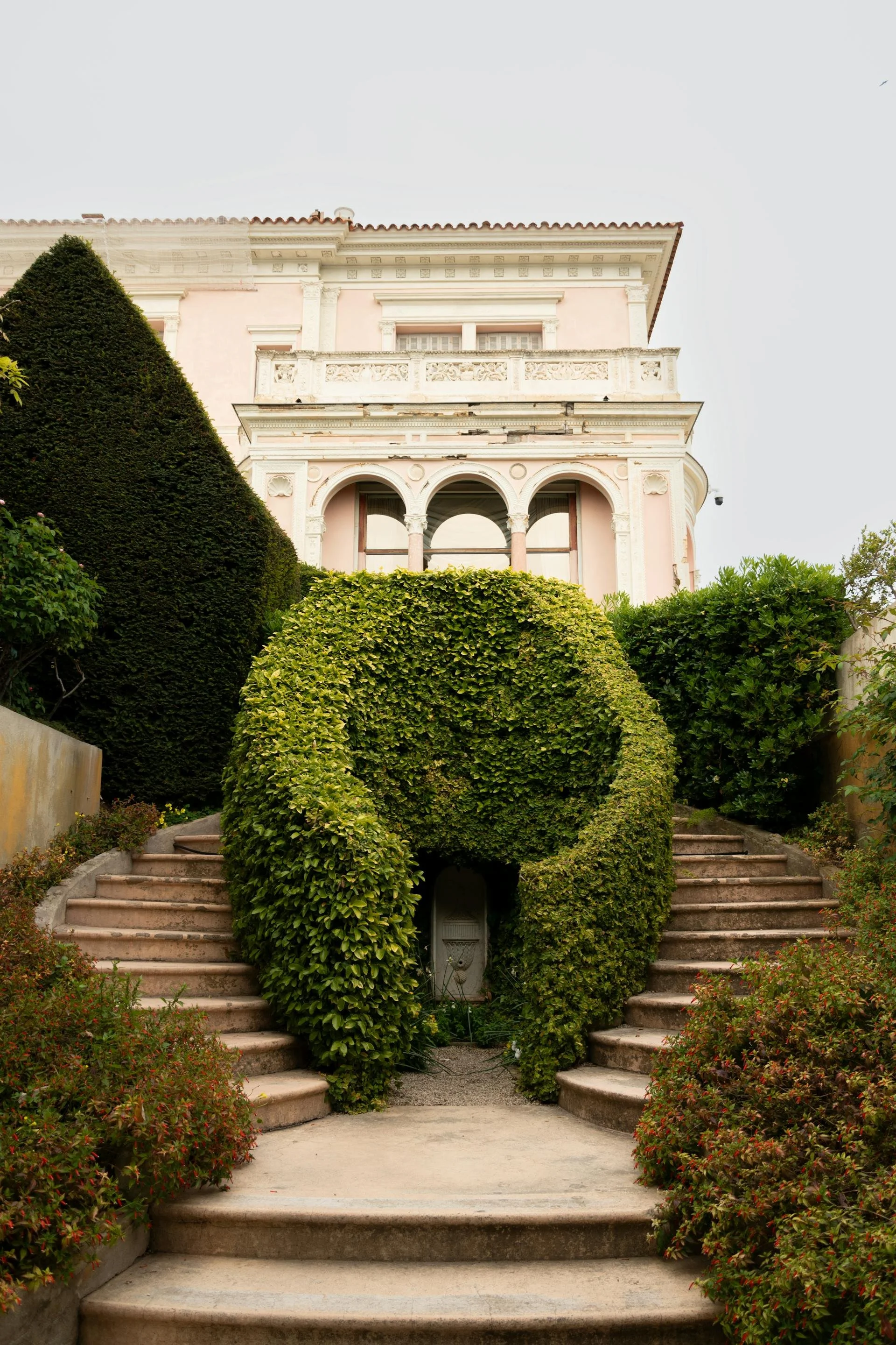 Wedding Website Design, Digital Wedding Stationery, Web Design and Branding for Wedding Professionals | Avelã White. Elegant villa with lush garden, featuring ornate archways and manicured hedges on a staircase.