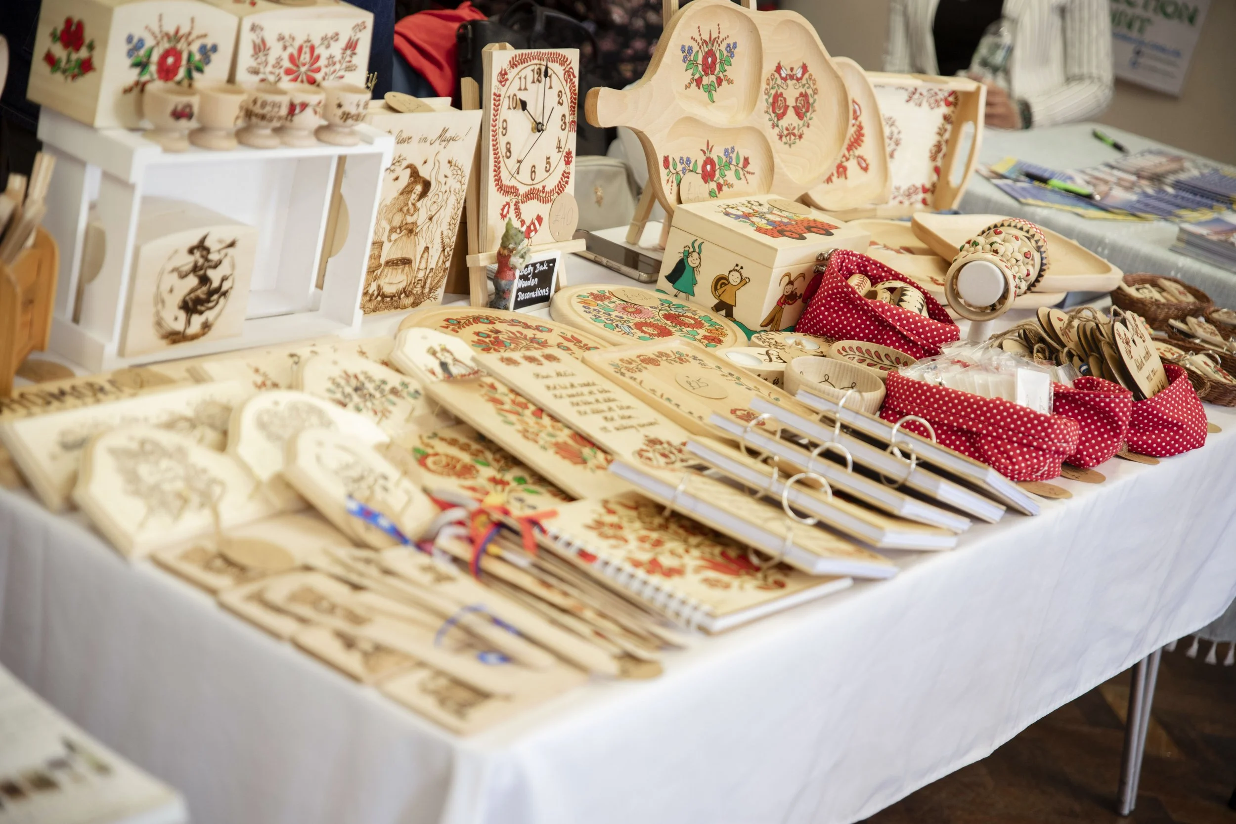 Display of handcrafted Hungarian wooden decorations and ornaments on a table at Magyar Cymru's 2025 Welsh-Hungarian Day craft fair in Cardiff.