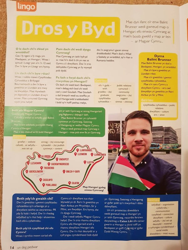 A page from a Welsh educational magazine featuring a story about Dyma Balint Brunner, with a photo of him holding a Welsh flag, a map of Wales highlighting Cymru, and Welsh text.