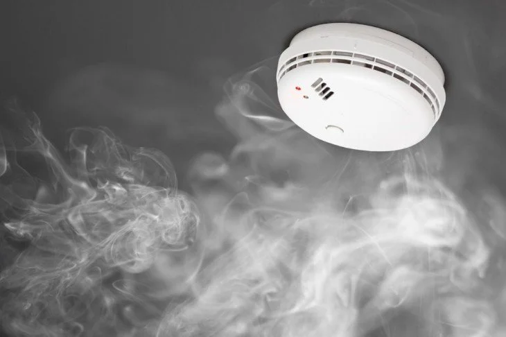 Smoke from a malfunctioning smoke detector with smoke and vapor visible in the air.