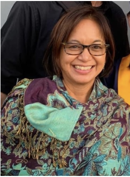 Smiling woman with glasses and shoulder-length hair, wearing a colorful patterned shawl.