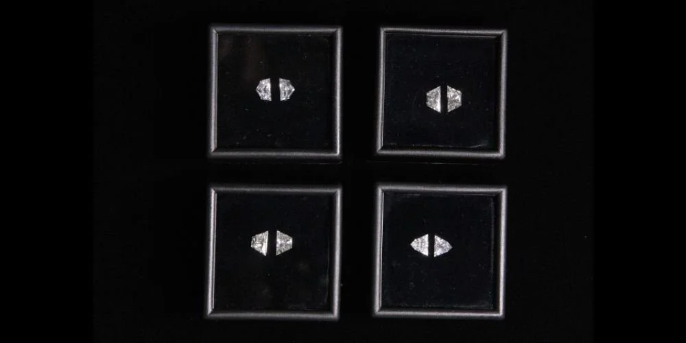 A black surface with four recessed square buttons, each with a white geometric symbol in the center.