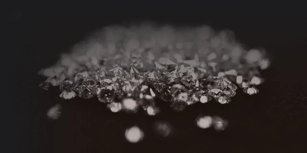 Close-up of scattered diamonds on a dark surface.