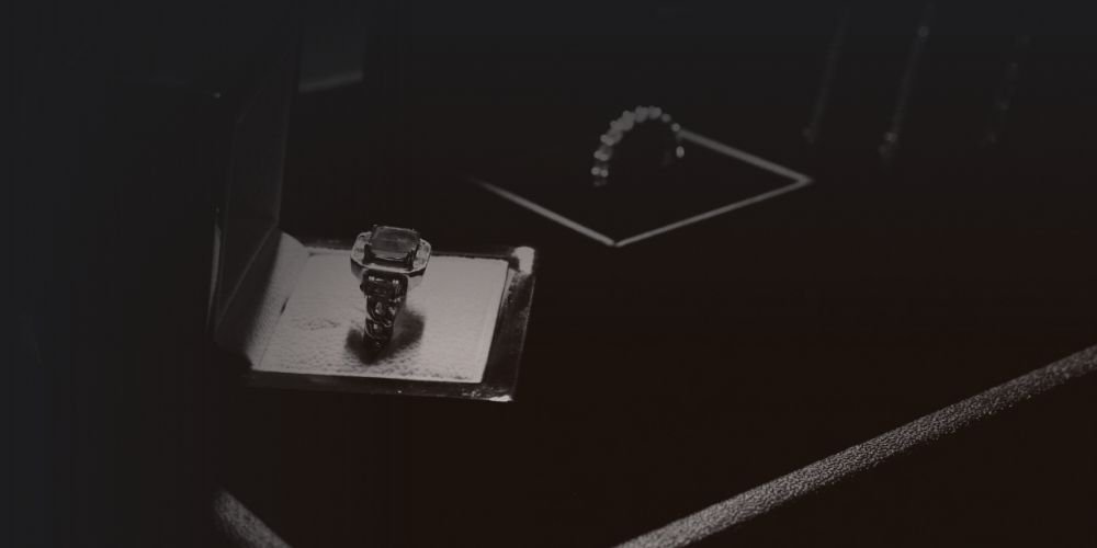 A jewelry display case with a ring on a stand and a bracelet in a box.