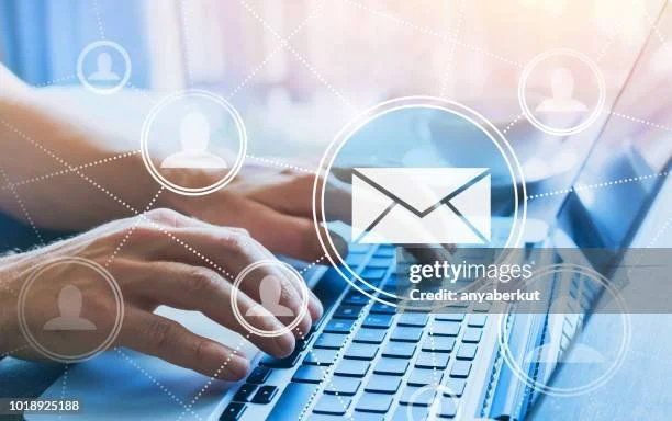 Hands typing on a laptop keyboard with digital icons of people and an email symbol overlaid.
