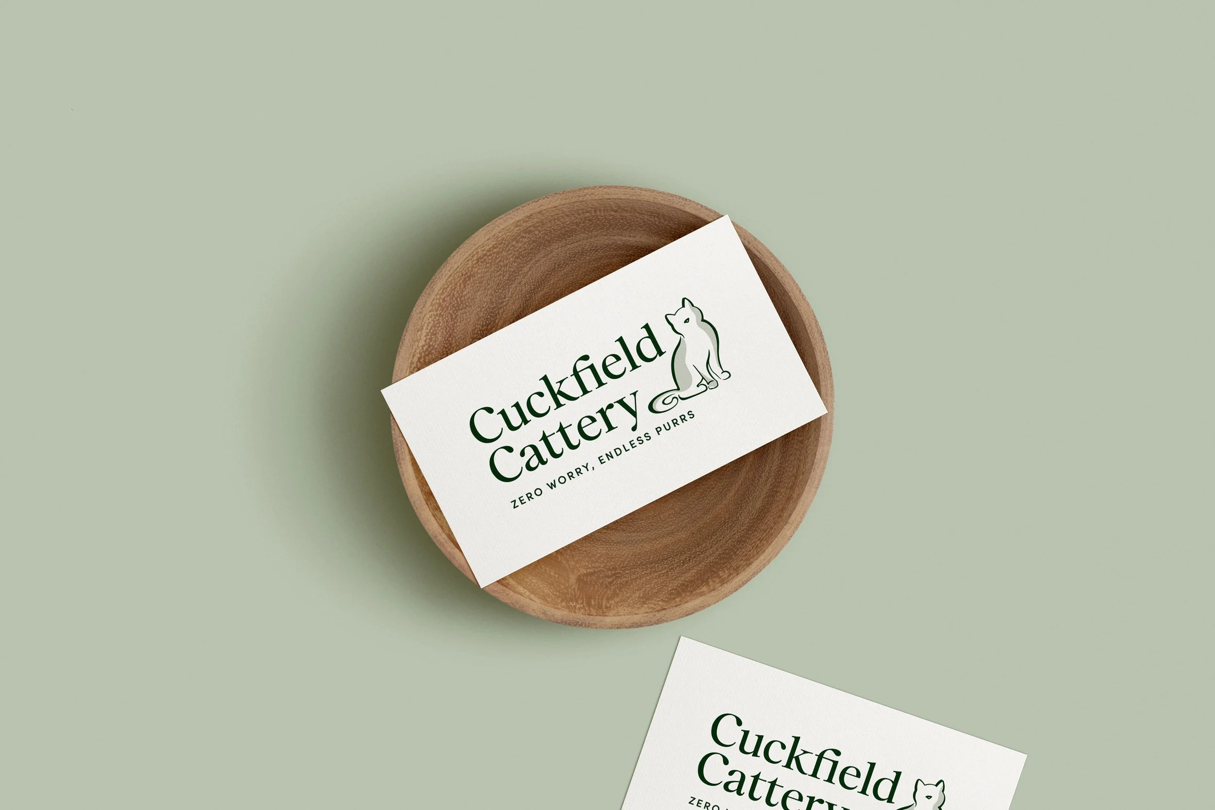 Business card for Duckfield Cattery with a cat illustration and the tagline 'Zero worry, endless purrs' on a wooden dish.