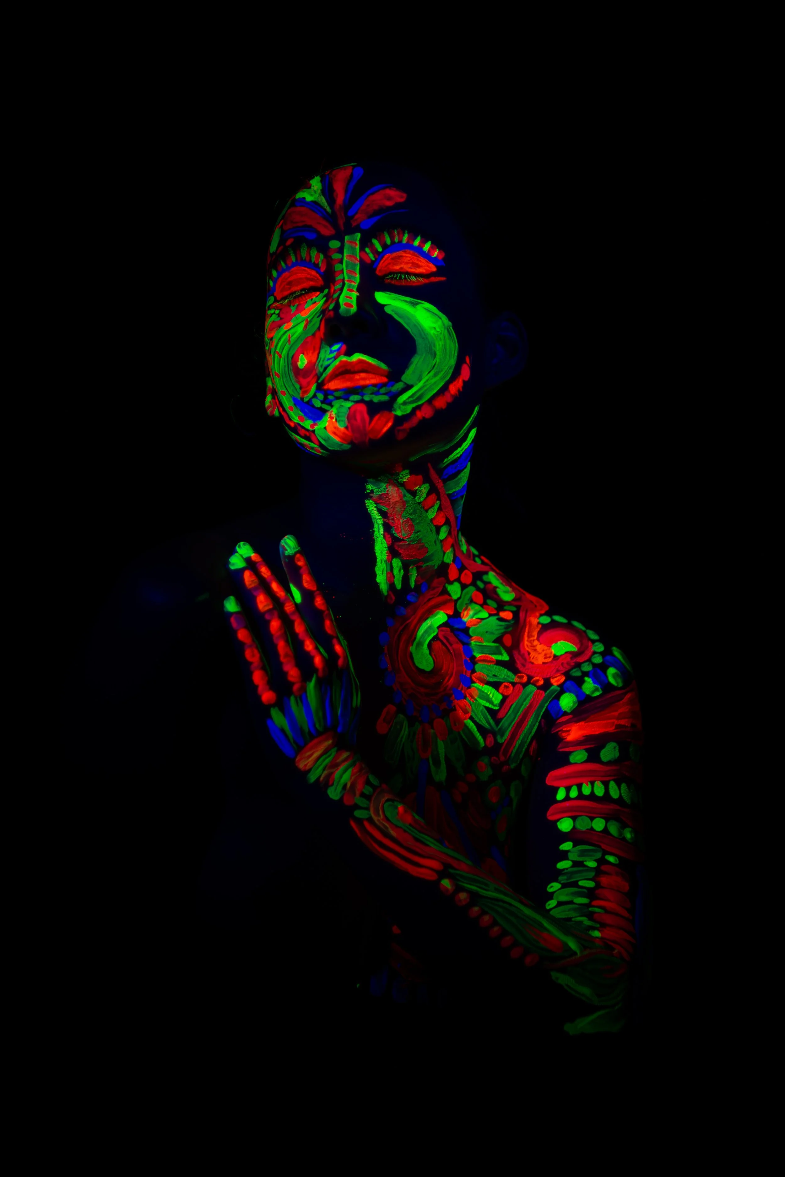 Person with face and body painted with neon colors under black light