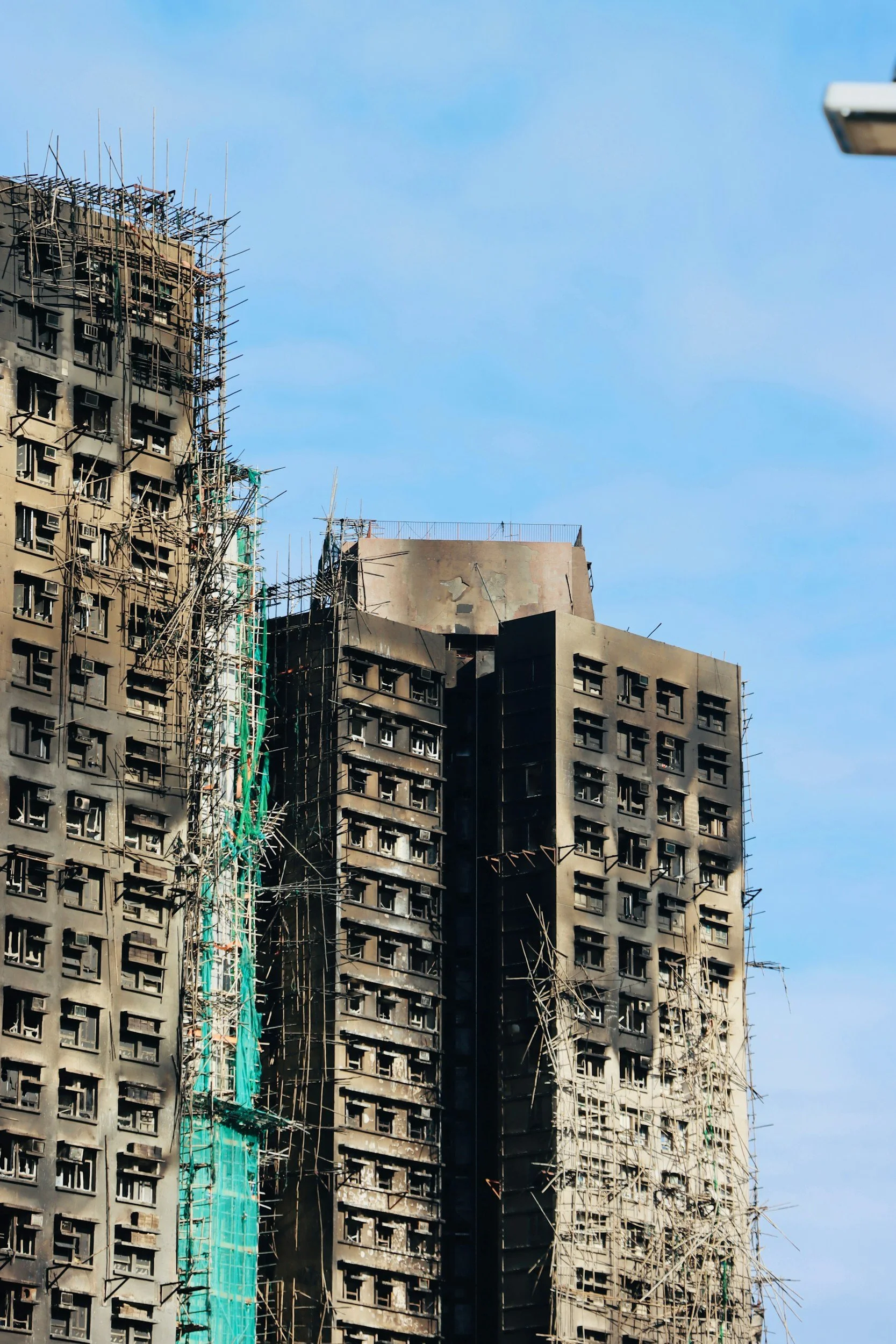 Burned high-rise building under construction with scaffolding and a blue sky in the background.
