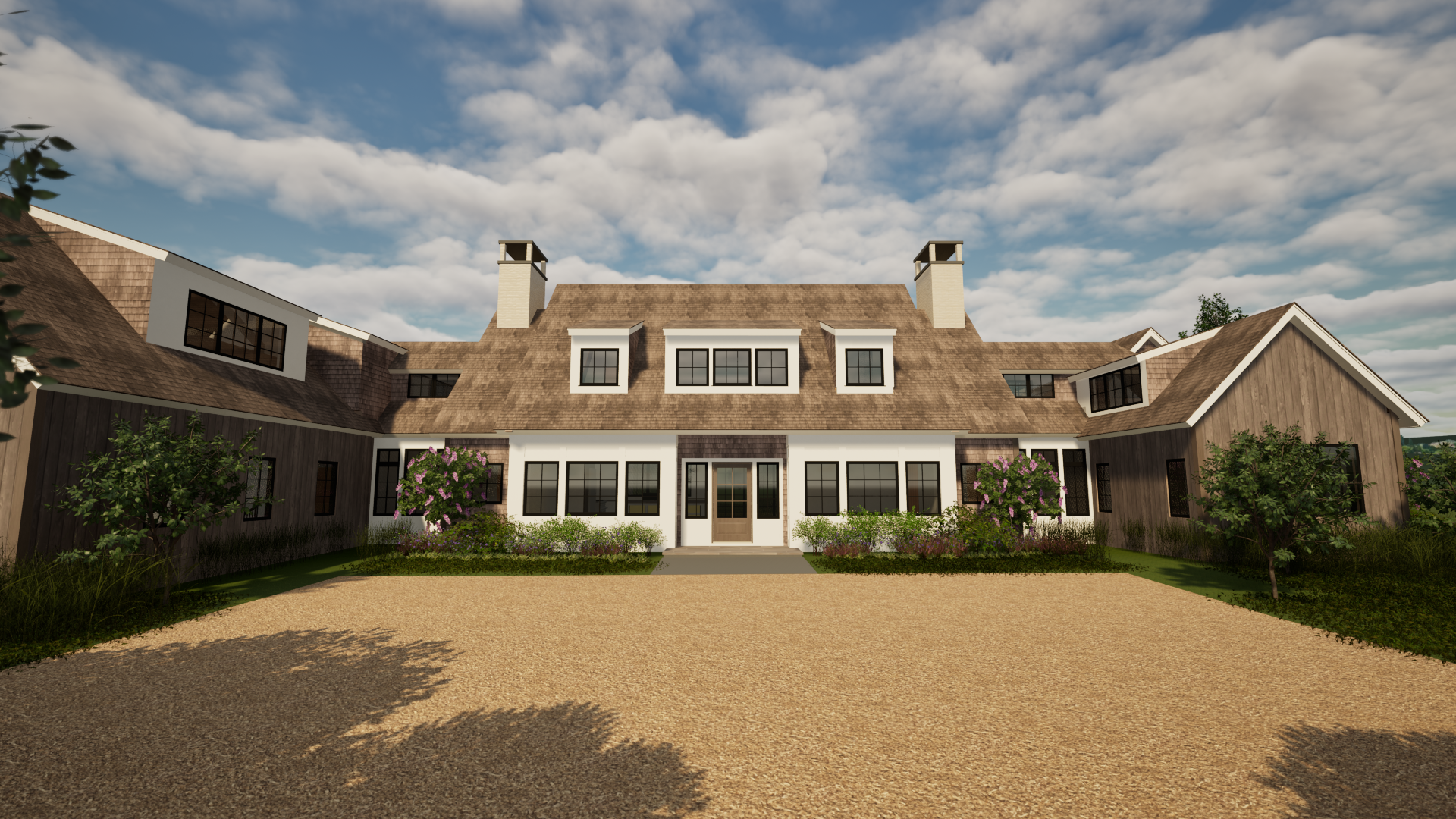 A large modern house with a brown shingle roof, white and wooden exterior walls, multiple large windows, and surrounded by lush greenery and flowering shrubs. The driveway is gravel, and the sky is partly cloudy.
