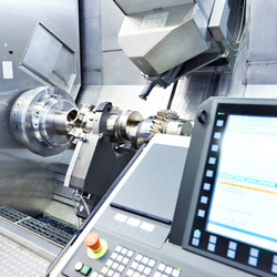 A CNC machine with a digital control panel and robotic arm working on a metal part.