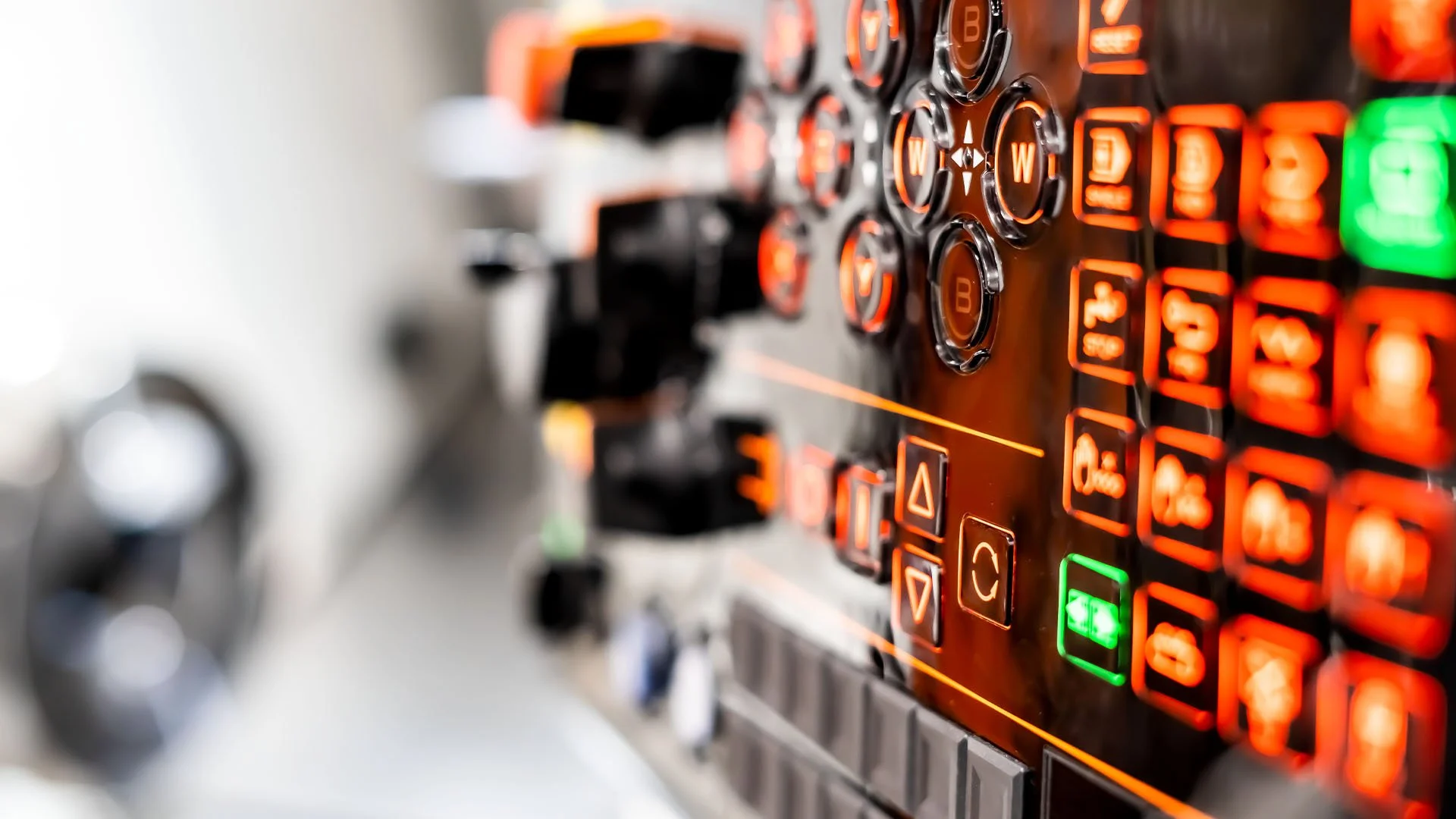 Close-up of a DJ mixer with illuminated buttons and knobs in red, green, and orange.