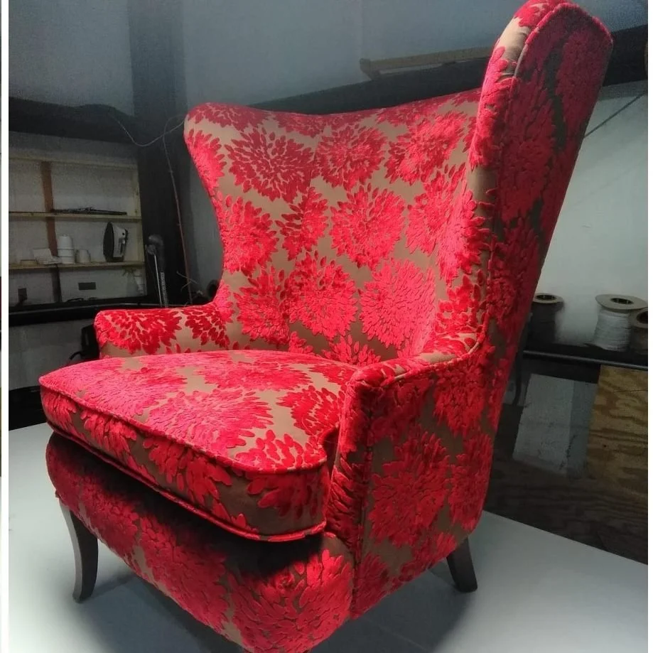 A red and beige upholstered wingback armchair with floral pattern.
