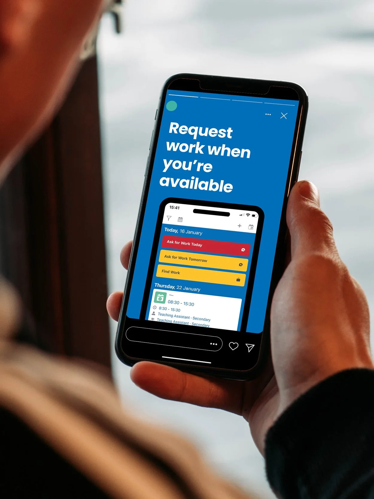 A person holding a smartphone displaying a scheduling app with the message 'Request work when you're available' in white text on a blue background.