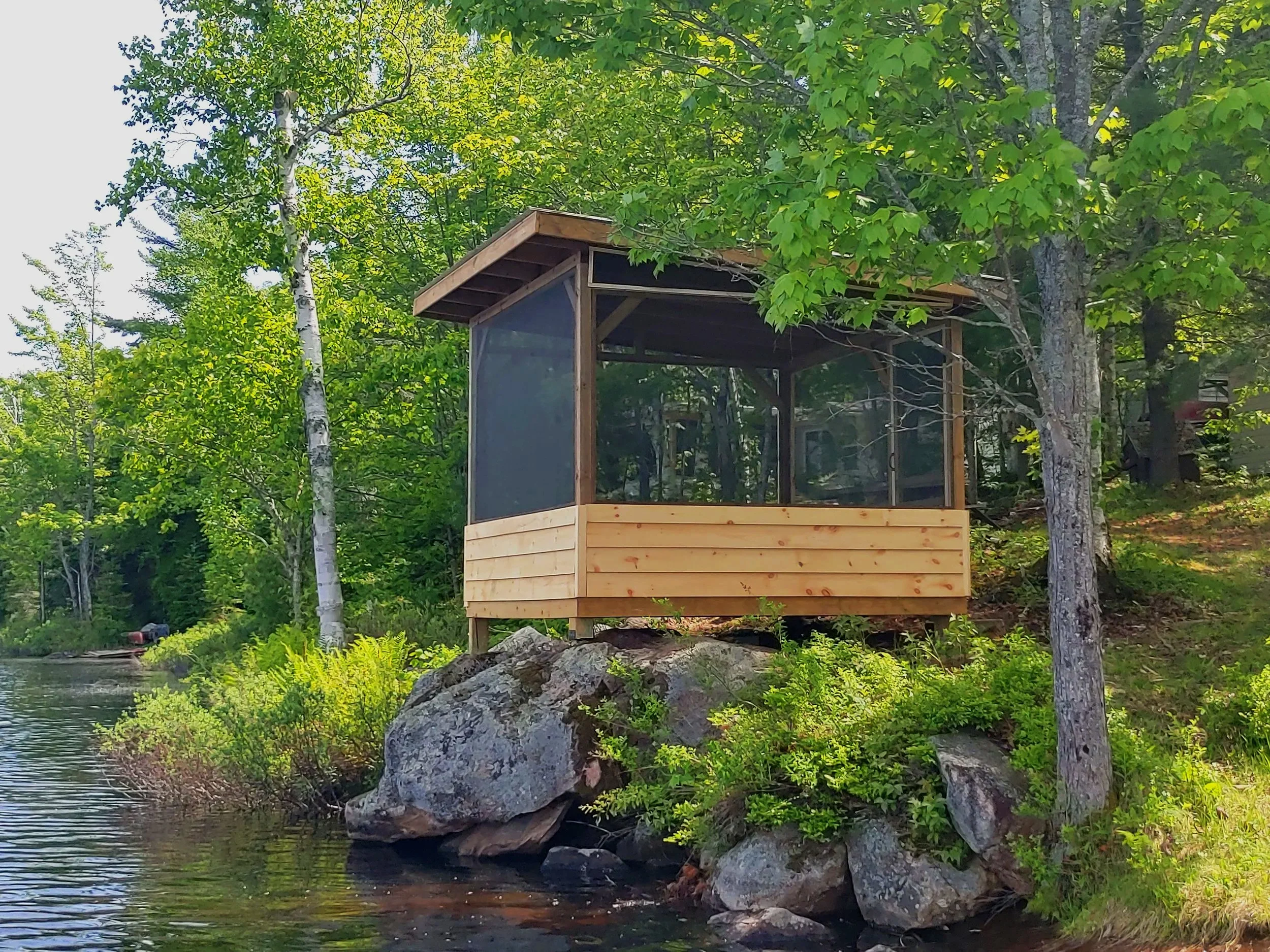 A screened-in gazebo on the shore of a Muskoka lake