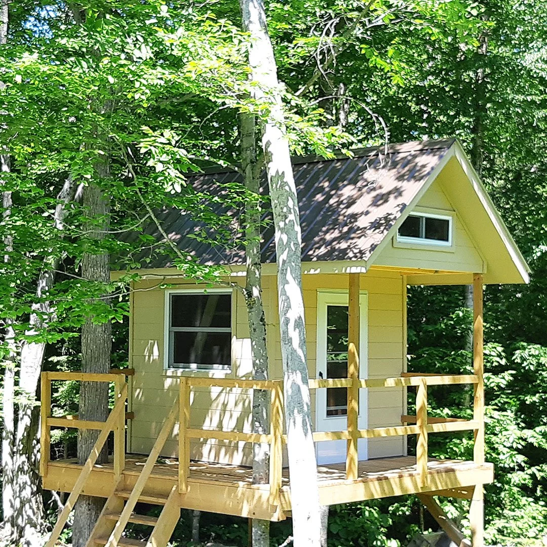 A small yellow bunkie in the trees