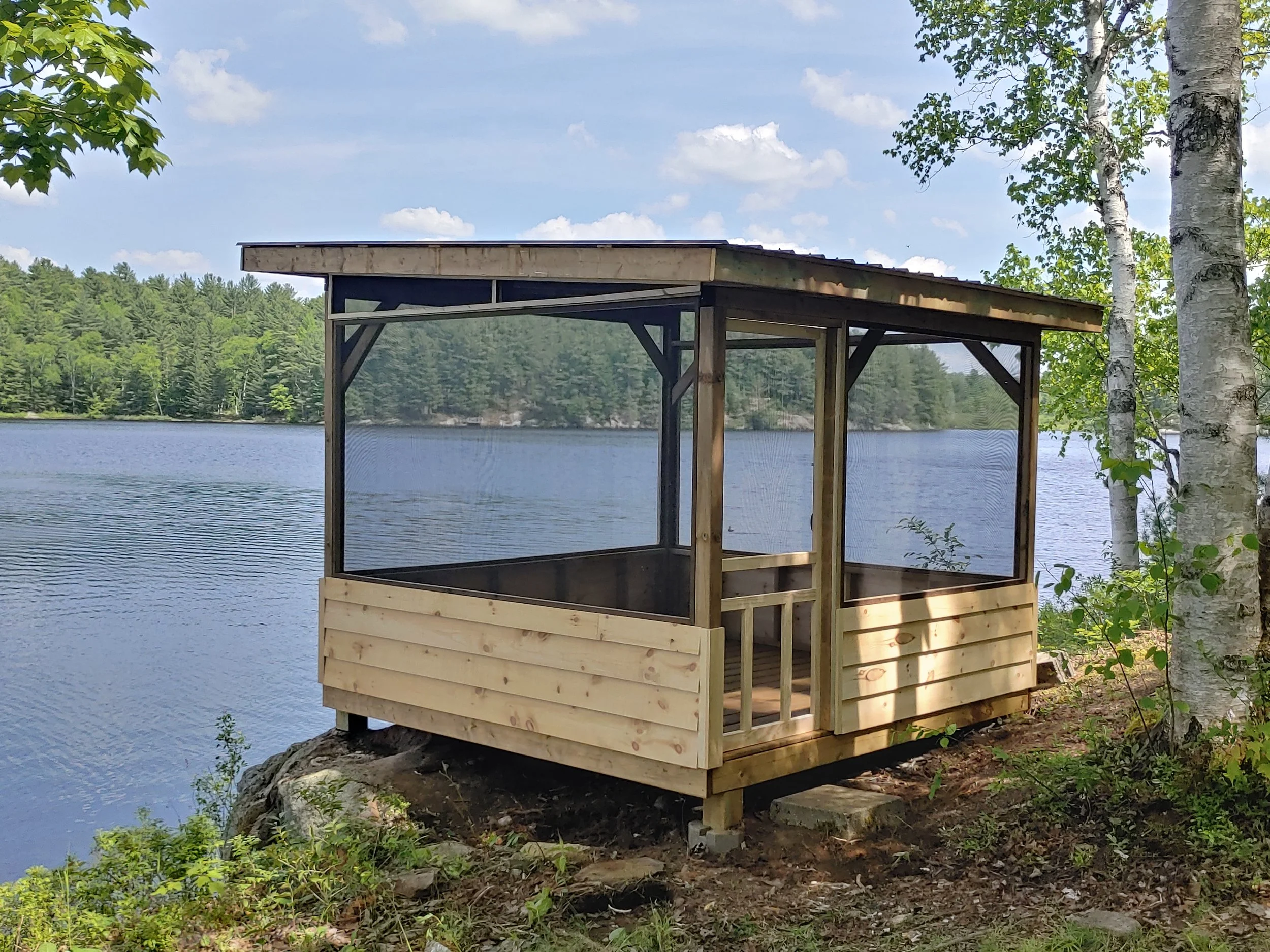 A screened-in Gazebo beside the lake