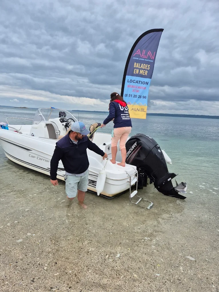 Deux personnes se préparent à embarquer sur un bateau à moteur au bord de la mer par temps nuageux, avec une bannière promotionnelle en arrière-plan.