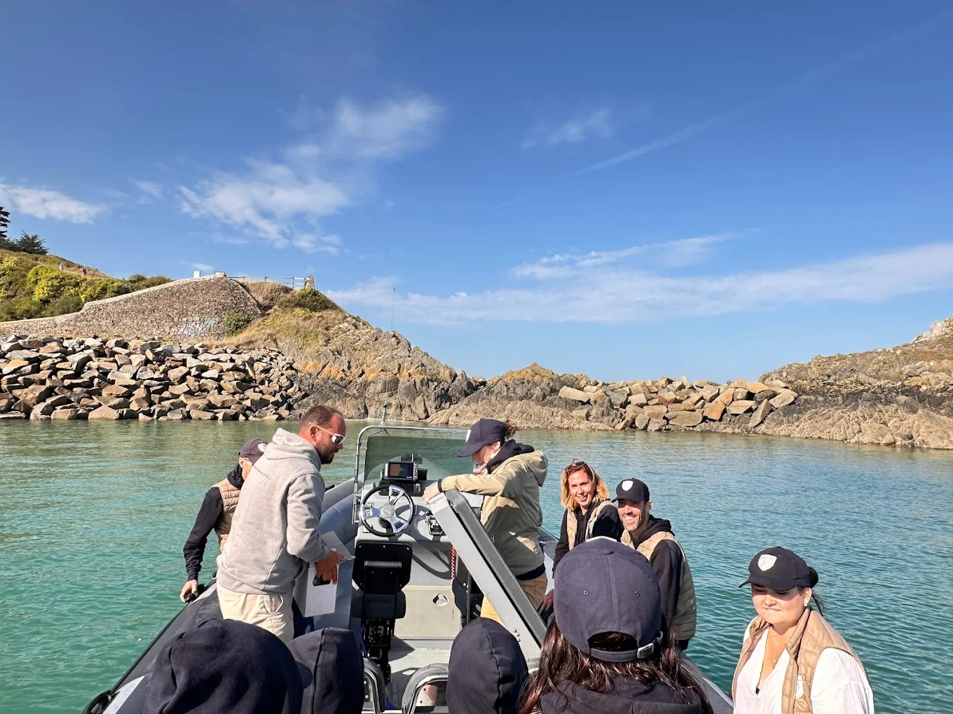 Groupe de personnes en bateau dans un paysage côtier avec rochers et ciel bleu