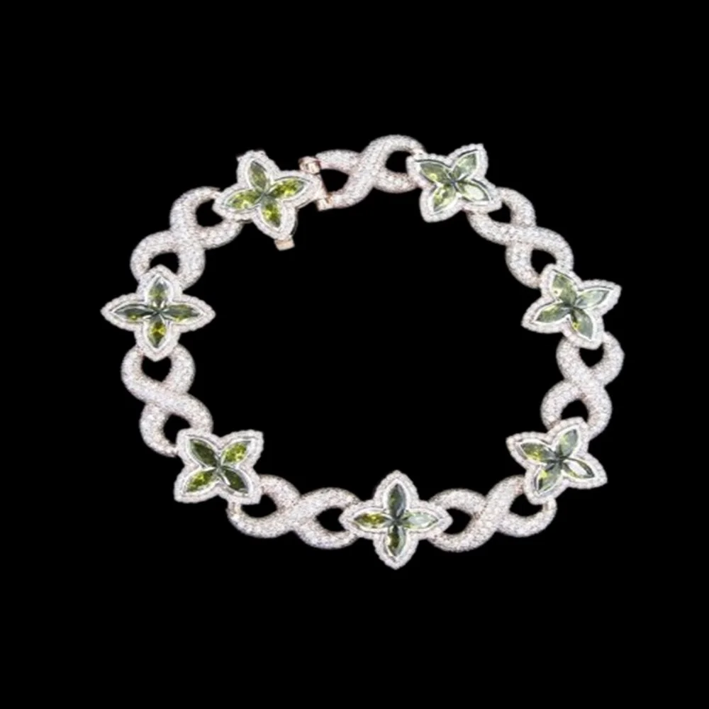 Silver bracelet with butterfly-shaped links and green accents on a black background.