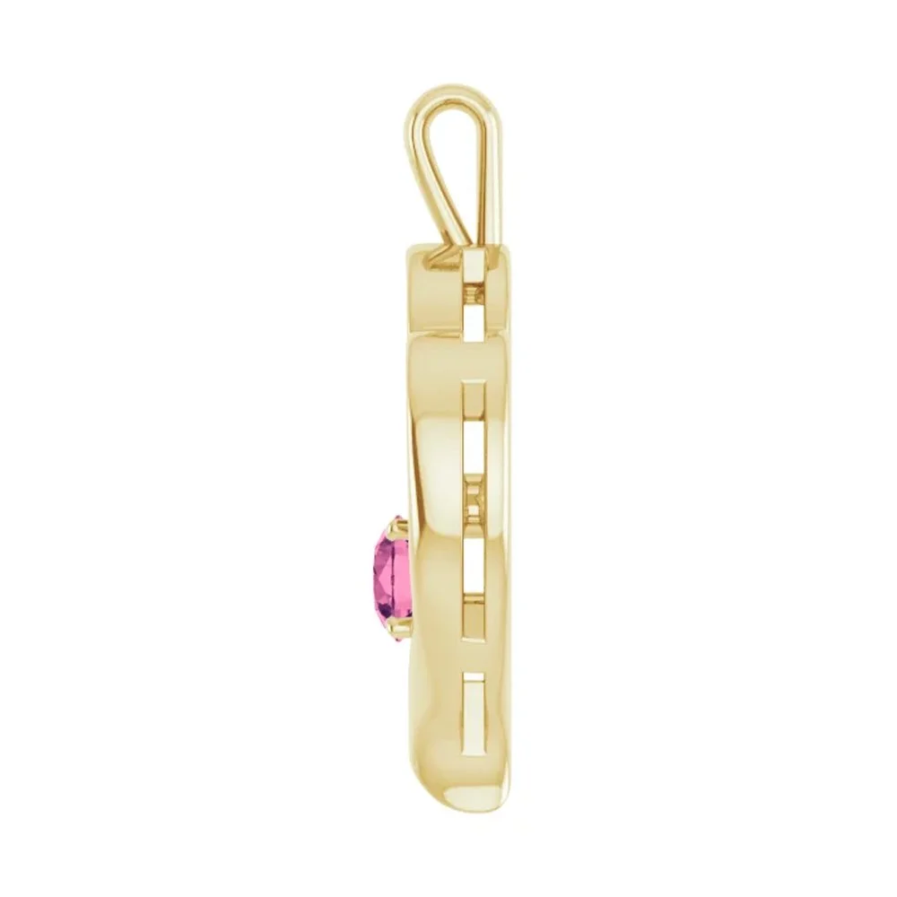 Gold safety pin with a pink gemstone attached.