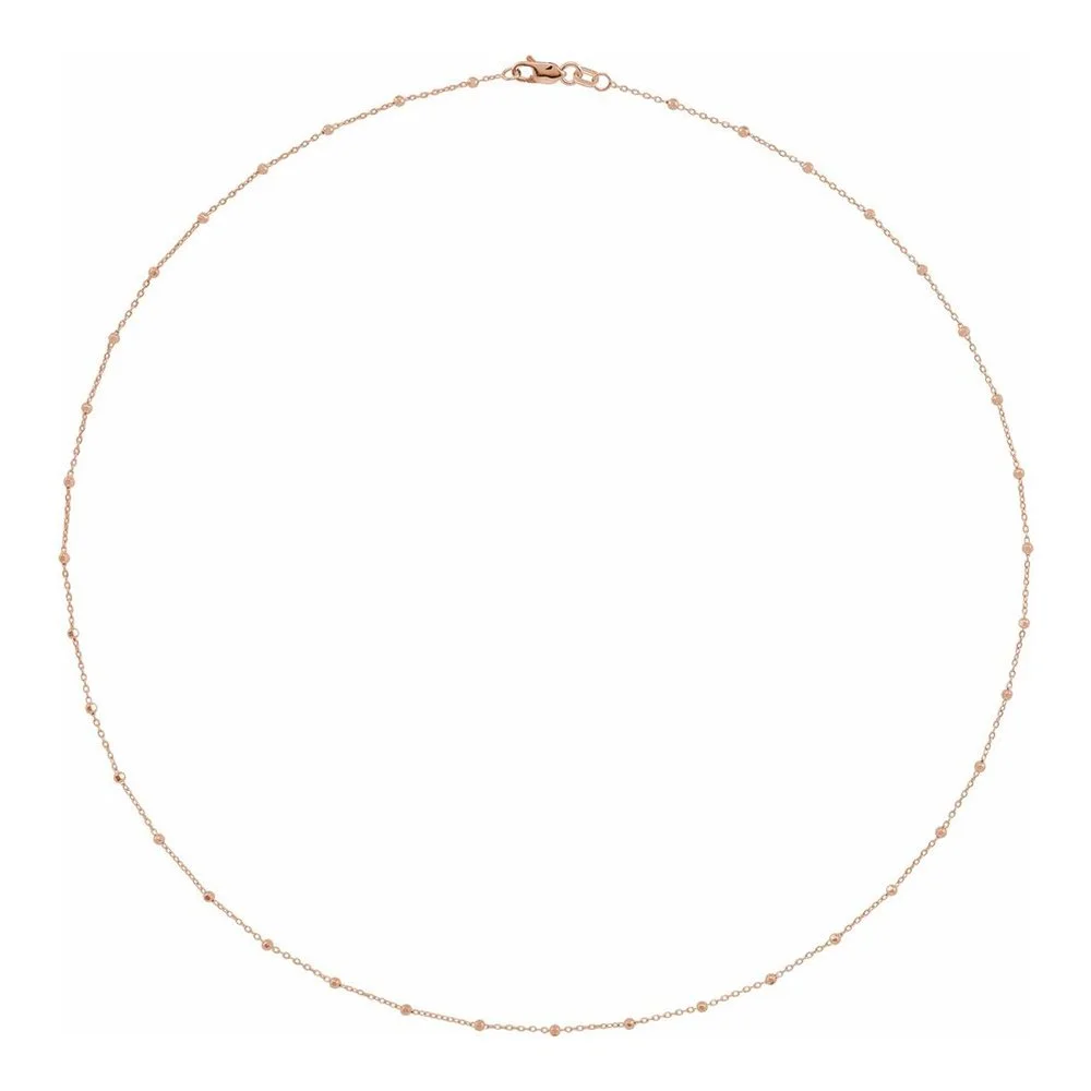 A delicate gold chain necklace with small beads evenly spaced along the chain.